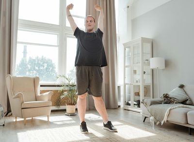 A man stretching his arms in a quiet, spacious room.